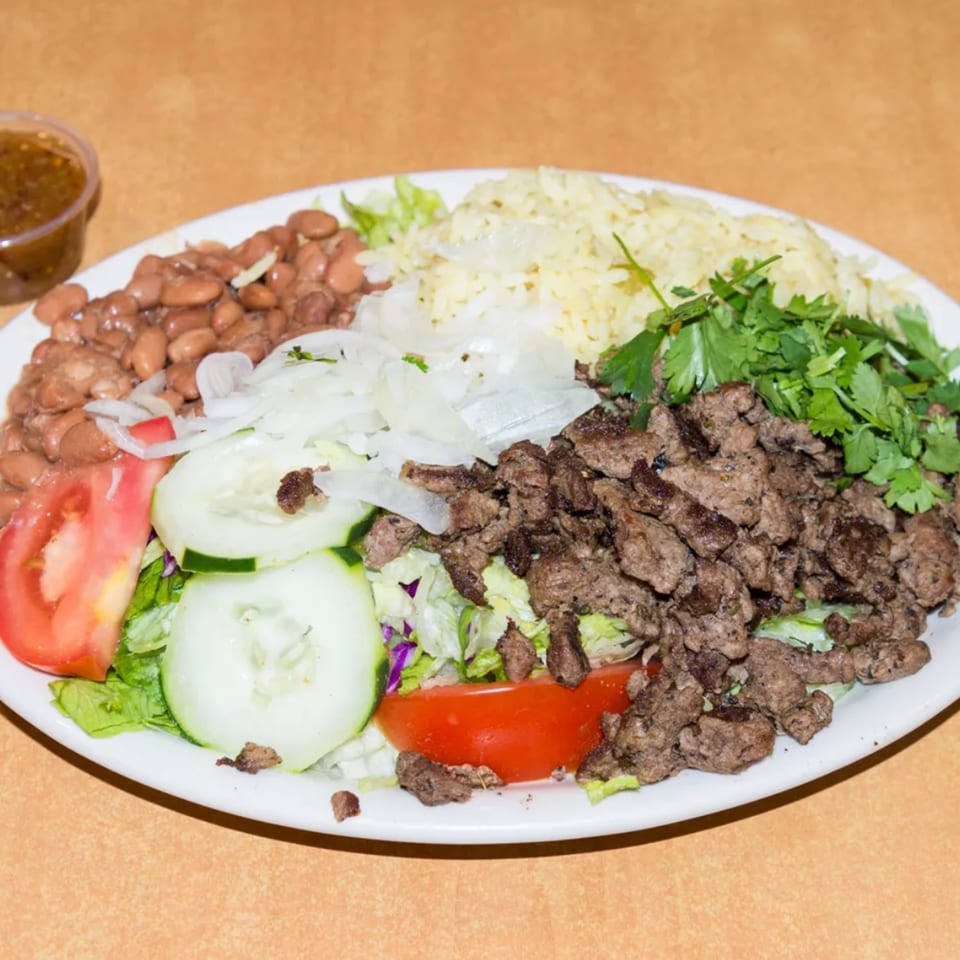A diner plate with rice, beans, chopped meat, lettuce, tomatoes, cucumbers, onions, and cilantro.